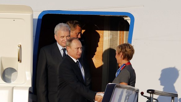 Russian President Vladimir Putin, foreground left, shakes hands with an aircrew member upon his arrival at the Beijing Capital International Airport in Beijing on Wednesday.