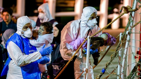 Rescuers help children to disembark in the Sicilian harbour of Pozzallo on April 20,  after 100 migrants, including 28 children, were rescued   by a merchant vessel.
