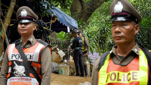 A Thai navy diver, centre, prepares his equipment at the heavily policed base camp at Tham Luang cave. 