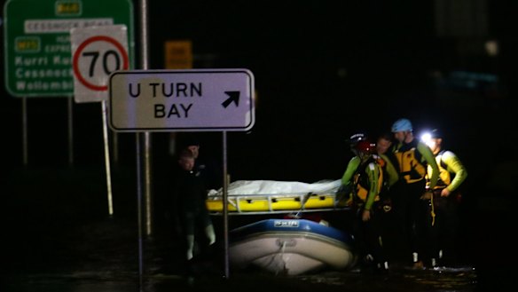 Police divers retrieve the body of an 86-year-old woman whose car was swept away.
