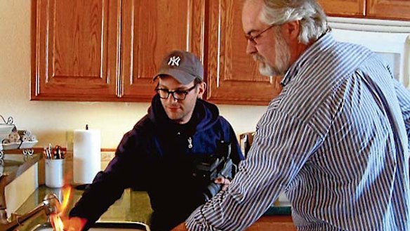Hot topic ... a householder lights tainted tap water for Josh Fox (left).