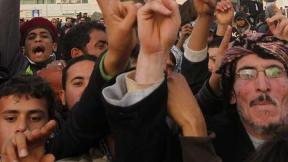 Protesters chant anti-government slogans while holding a banner depicting Libyan leader Muammar Gaddafi in Tobruk.