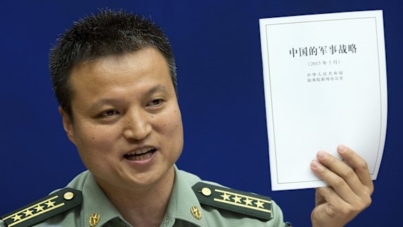 China's Defence Ministry spokesman Yang Yujun holds up China's Military Strategy white paper during a press conference in Beijing on Tuesday.