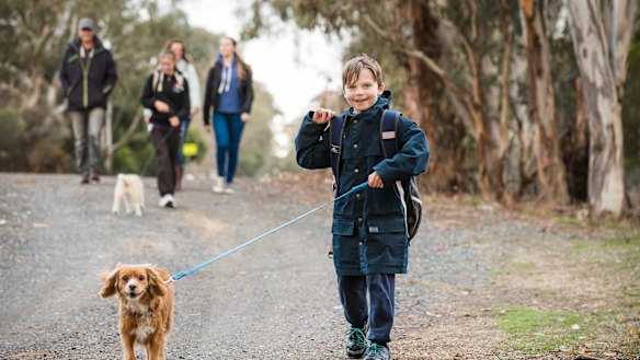 Timothy Pengilly races ahead with his dog Charlie as his parents Geoff and Roz Pengilly walk his sisters Angela and Hannah home from the bus stop. 