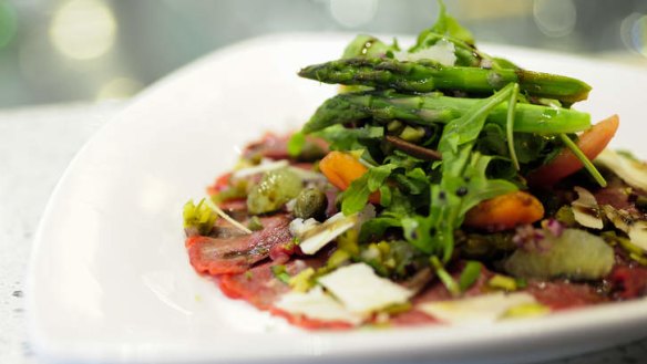 Beef carpaccio topped with rocket and asparagus.