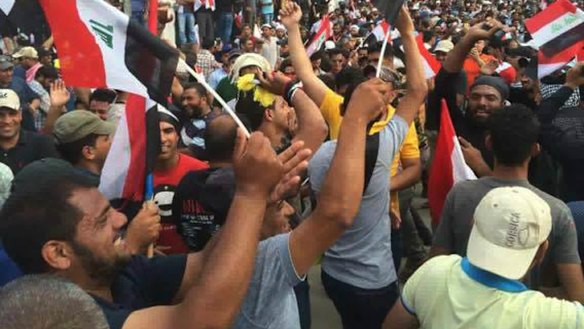 Protesters raise the Iraqi flag outside parliament in Baghdad's Green Zone.