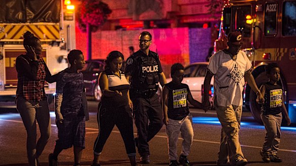 Police escort civilians away from the scene of a shooting. 