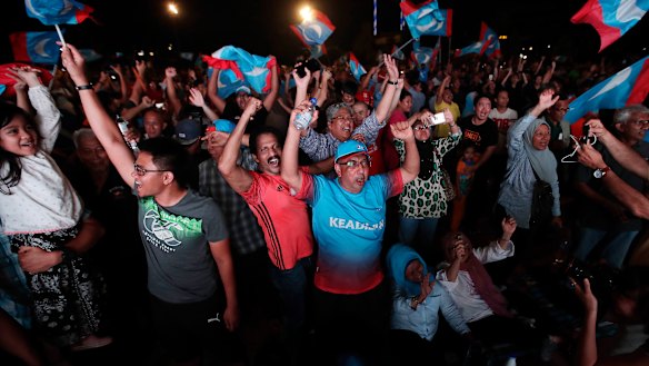 Opposition party supporters cheer and wave their party flags after Mahathir claimed victory.
