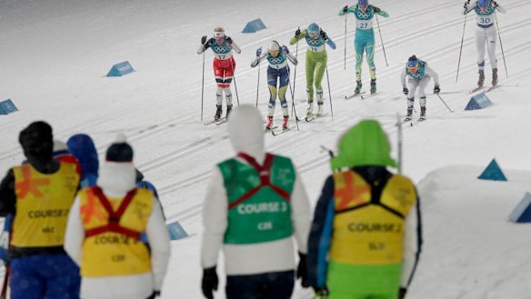Workers watch the women's cross-country skiing.