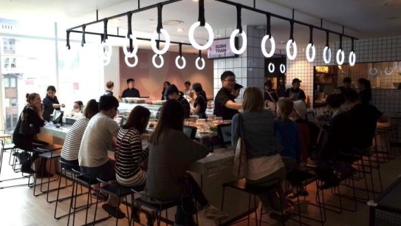 Neon circles glow above the sushi train at Tetsujin.