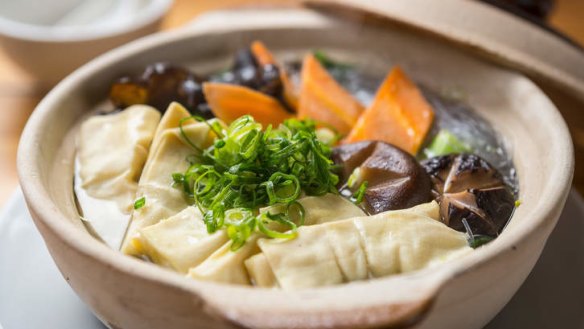 Clay pot filled with pork broth, greens and bean curd sheets.