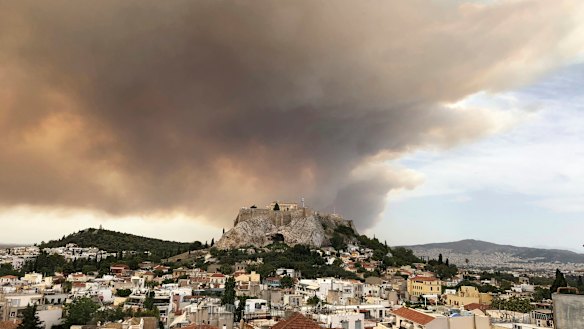 A pall of smoke turns large parts of the sky orange, with the ancient Acropolis hill at centre.