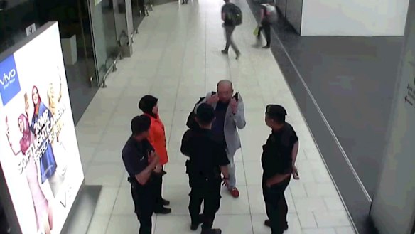 Kim Jong-nam, in grey, gestures towards his face while talking to airport security shortly before his death.