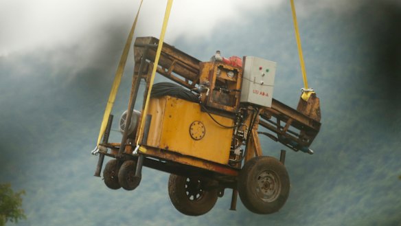 A military transport helicopter carries a drill machine to be used for the rescue.