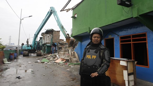Officers with heavy equipment destroy buildings in Kalijodo after residents and sex workers were evicted.