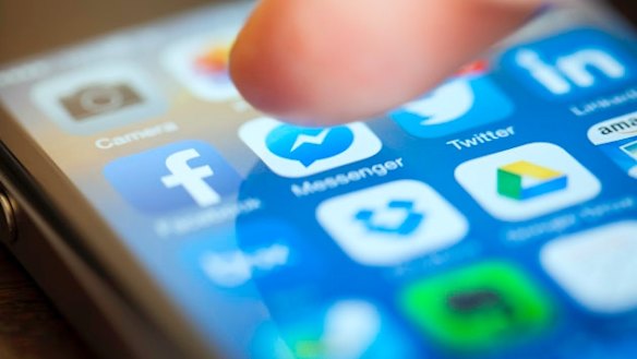 A person using social media, ready to push the Messenger app icon on the home screen of an iPhone model device.