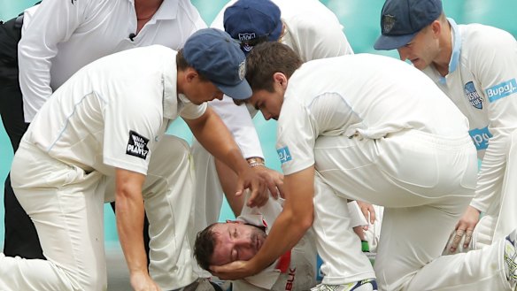 NSW players assist Hughes on the field.