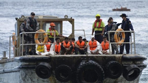 Australian customs officials and navy personnel escort asylum-seekers onto Christmas Island in August, 2013.