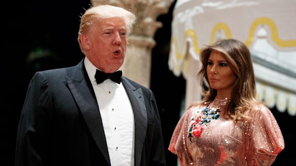 First lady Melania Trump looks on as President Donald Trump speaks with reporters after arriving for a New Year's Eve gala at his Mar-a-Lago resort.