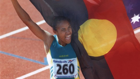 Cathy Freeman holds up the Aboriginal flag alongside the Australian flag after her 400m win at the 1994 Commonwealth Games.
