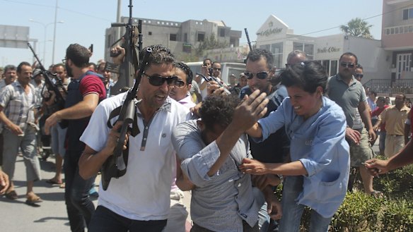 Police officers surround a man they suspect to be involved in opening fire on a beachside hotel in Sousse, Tunisia.
