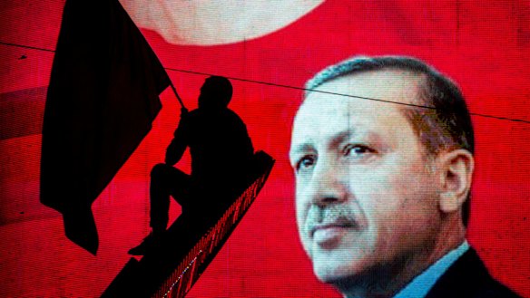 A supporter of Turkish President Recep Tayyip Erdogan waves a flag against an electronic billboard during a rally in Ankara, Turkey.