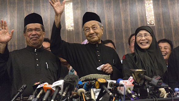 Newly-elected Mahathir Mohamad, centre, waves next to Deputy Prime Minister Wan Azizah, right, in Kuala Lumpur on Friday.