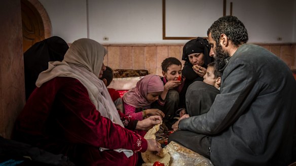 Younes Omar and his family, who reportedly escaped one of the last contested areas of Raqqa, break bread at a mosque  being used as a reception centre  on the outskirts of  the city.