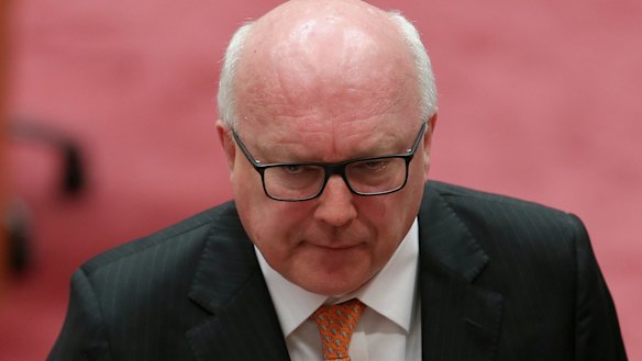 George Brandis was supposed to take up his post as High Commissioner to the UK next week but he has injured his heel playing tennis. 