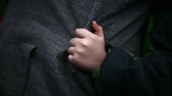 A boy holds on to a man's coat at a makeshift memorial near Sandy Hook Elementary School, scene of last week's mass shooting.