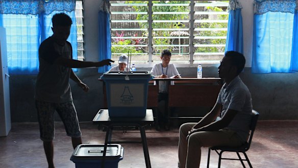 A man casts his ballot as an electoral worker, left, looks on during the presidential election at a polling station in Dili, East Timor.