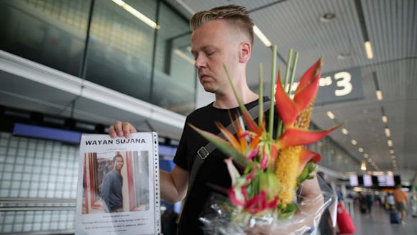 Dutchman Arthur Laumann holds a floral tribute and photograph of family friend Wayan Sujana of Bali, believed to be missing on Malaysia Airlines flight MH17 at Schiphol Airport in Amsterdam, Netherlands. Malaysia Airlines flight MH17 was ravelling from Amsterdam to Kuala Lumpur.