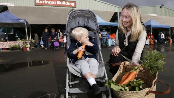 Cameron Featherston, 18 months, gets a carrot from mum Anna Featherston of Campbell after shopping at the Capital Region Farmers Market.