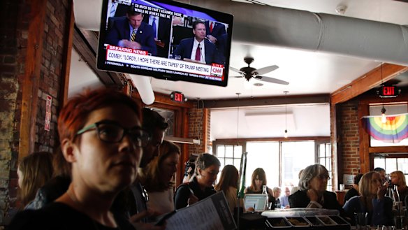 People watch live television broadcast of Mr Comey testifying in a Washington DC bar. 