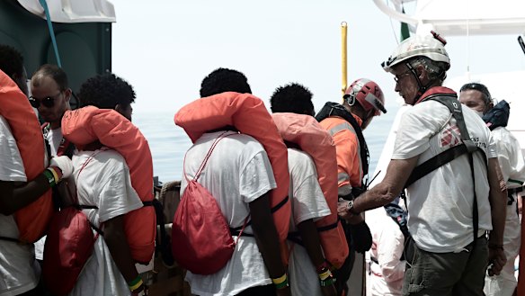 Migrants are transferred from the Aquarius to an Italian coast guard vessel at sea so they can be taken to Spain.