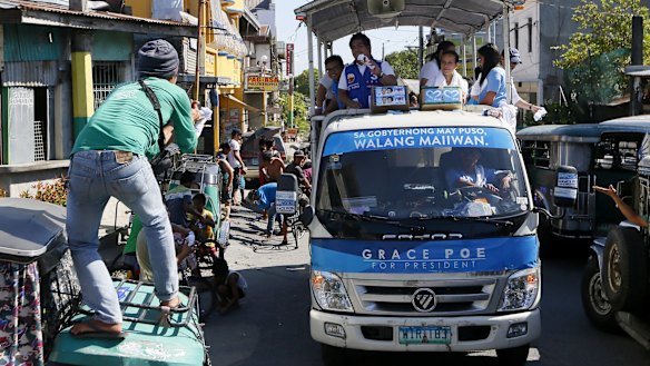 A supporter catches a souvenir T-shirt thrown by presidential candidate Senator Grace Poe, second from right, during her campaign sortie around Cavite province, south of Manila.