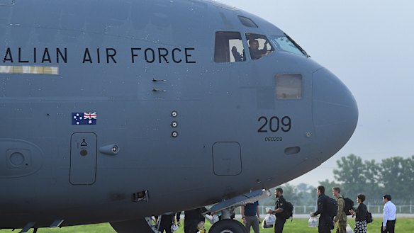 The Australian Federal Police dive team and support staff walk over the tarmac at Chiang Rai airport to board an Australian RAAF plane bound for Canberra.