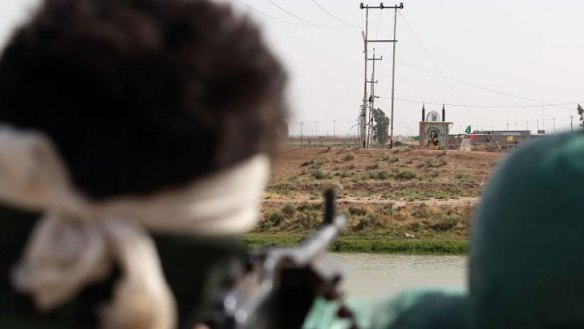 An Iraqi Turkmen fighter looks at an icon of the seventh century Imam Ali bin Abi Talib, 25 km south of Kirkuk. ISIL took control of an Iraq-Syria border crossing after Syrian rebels withdrew overnight.