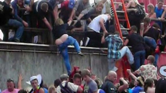People try to escape over a wall  after a panic at Loveparade 2010 in Duisburg, Germany.
