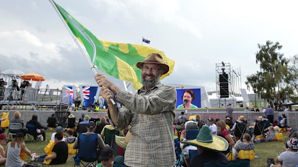 Ian Robertson of Morisset waves the Aboriginal and a Green and Gold flag.  