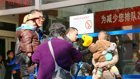 Families with young children gather outside a paediatric hospital in central Beijing. 