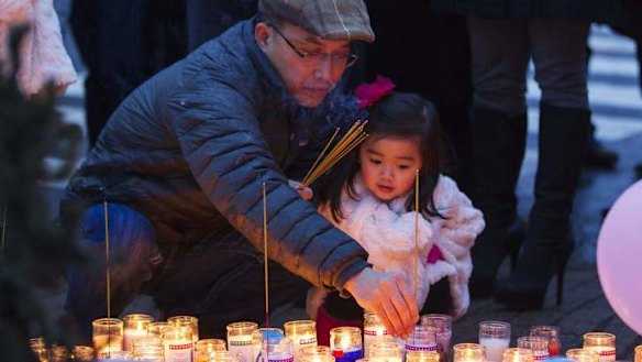 A mourner places joss sticks at a memorial for victims of the recent mass shooting.