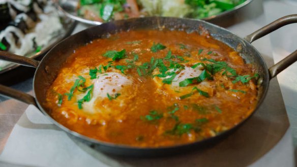 Shakshuka is served in the pan with a side of Israeli salad.