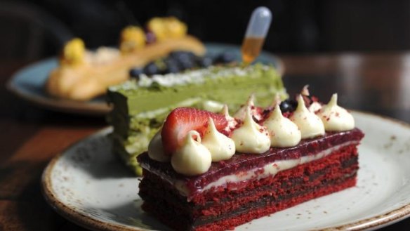 A selection of Patissez cafe's cakes, including at front a red velvet cake with Callebaut chocolate ganache, cream cheese frosting and tangy raspberry gel. 