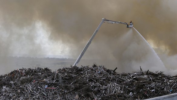CFA workers high above the massive pile of wood. 