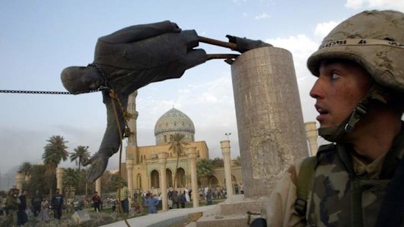 A US soldier watches as a statue of Iraq's President Saddam Hussein falls in central Baghdad in 2003.   