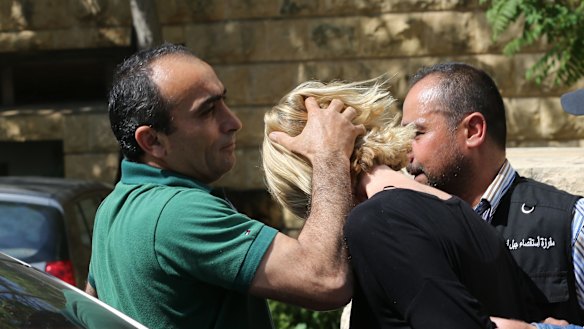 A Lebanese plainclothes policeman prevents Tara Brown from looking towards journalists as she was taken from the courthouse while under arrest in Lebanon.