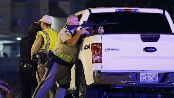 A police officer takes cover behind a truck. 