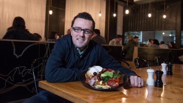 Dave Makin, co-owner of Axil Coffee Roasters, poses for a photo with a plate featuring all of the sides they offer for breakfast at the iconic Hawthorn roastery.