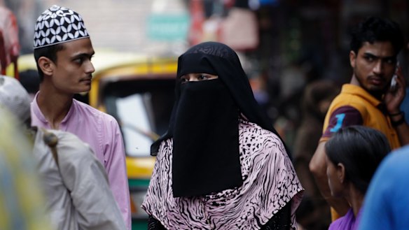 An Indian Muslim woman walks at a market area in Delhi, India.